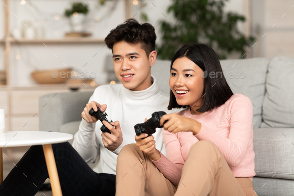 Chinese Boyfriend And Girlfriend Playing Video Games Sitting At