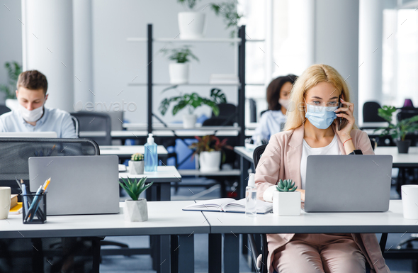 Working with client by phone remotely during COVID-19 outbreak. Millennial woman in protective mask - Stock Photo - Images