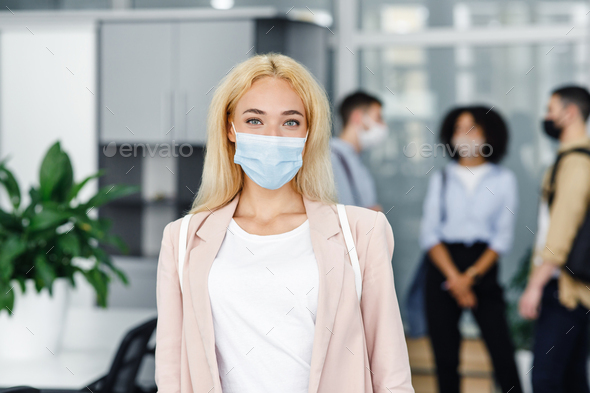 Modern manager returns to work after quarantine. Focus on attractive blonde woman in protective mask - Stock Photo - Images
