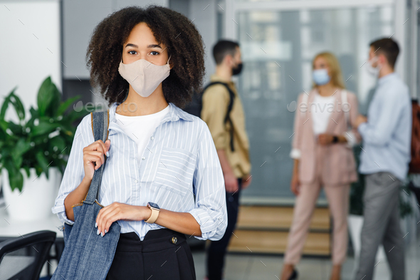 Social distancing and office work with colleagues. Attractive young african american woman with bag - Stock Photo - Images