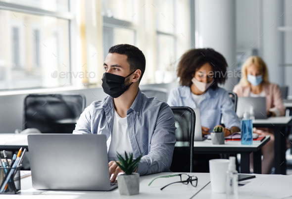 New rules for working in office and create a new idea. Arabian guy in protective mask looks out the