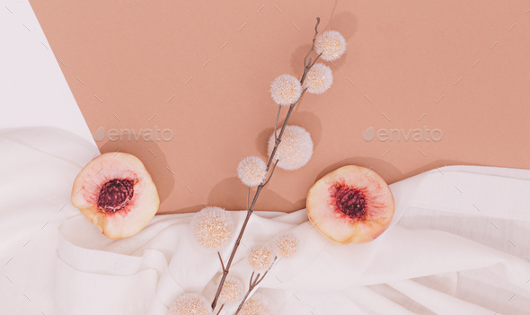 Still life scene with fresh peach and decor flowers on white textile  background. Minimal aesthetic. Stock Photo by EvgeniyaPorechenskaya