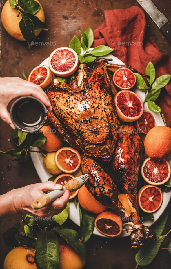 Womans hand putting oil on whole roasted turkey for holiday - Stock Photo - Images