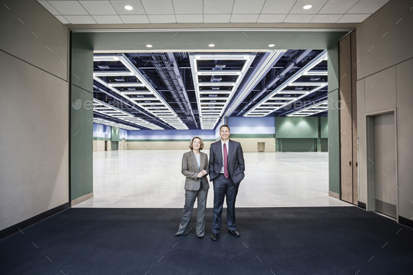 Two people standing in the entrance to a large convention center arena.