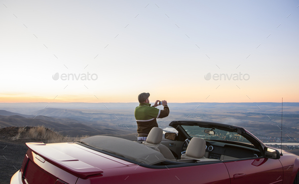 A driver stops to take a photograph at sunset , road trip with his convertible sports car. - Stock Photo - Images