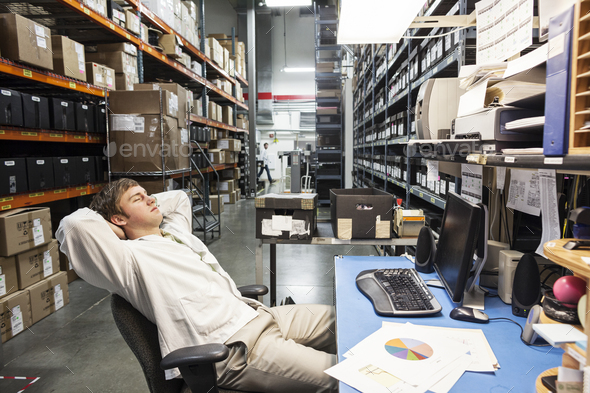 A male technician relaxing at his desk in the parts department or storage facility