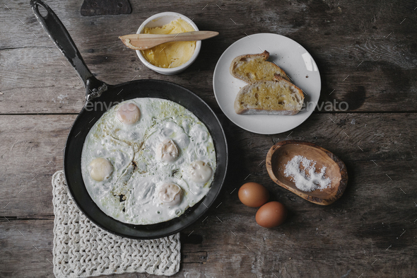 A dish of eggs, bread and sauce laid out on a table.