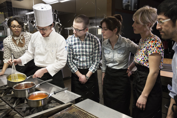 A chef and students at a cookery class in a commercial kitchen