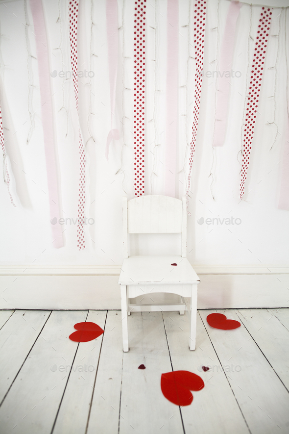 Empty chair in a photographers studio, fairy lights and red streamers on the wall