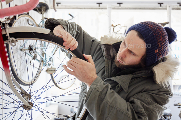 A young man working in a cycle shop, repairing a bicycle.