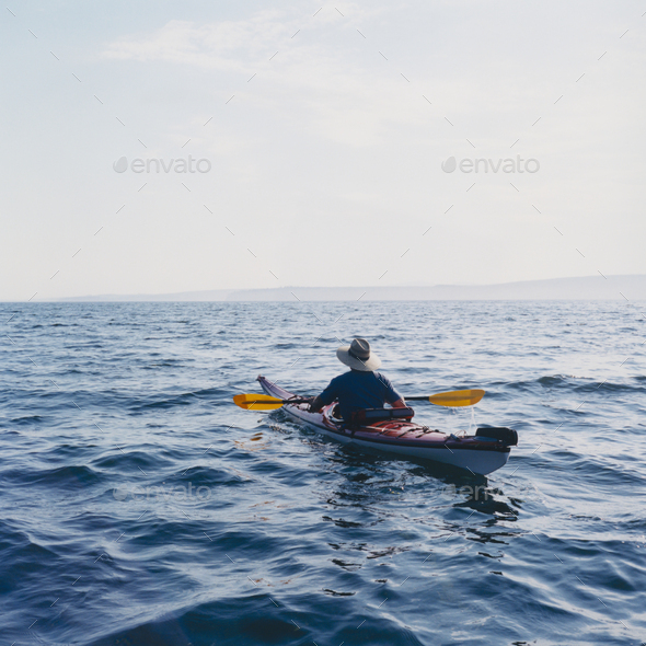 Man sea kayaking in Puget Sound at dusk - Stock Photo - Images