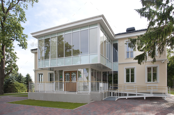 A traditional house with a modern glass extension, two storeys, with glass walls.