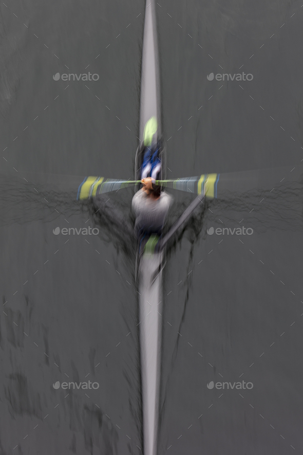 A single scull boat and rower on the water, view from above. Motion blur