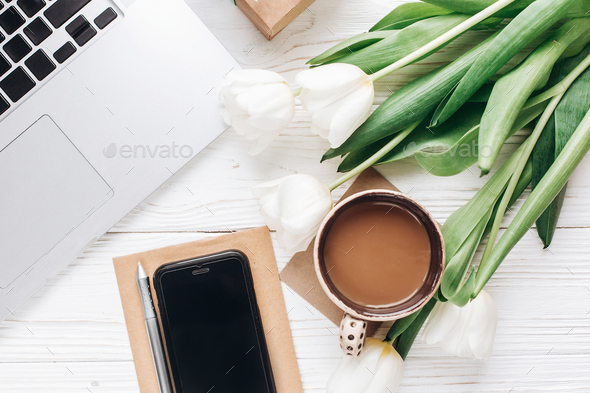 phone screen and laptop with morning coffee and tulips on white wooden rustic background - Stock Photo - Images