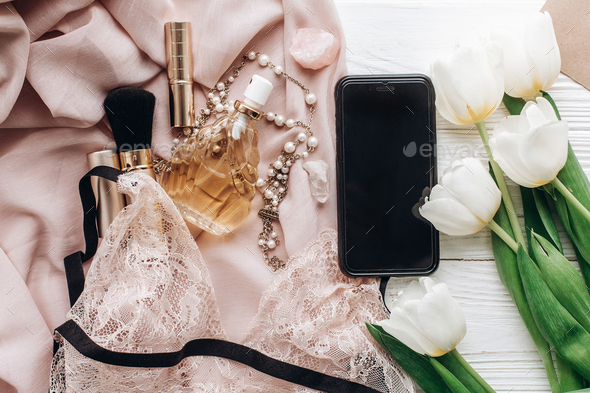 phone screen and stylish woman lace lingerie jewelry and perfume