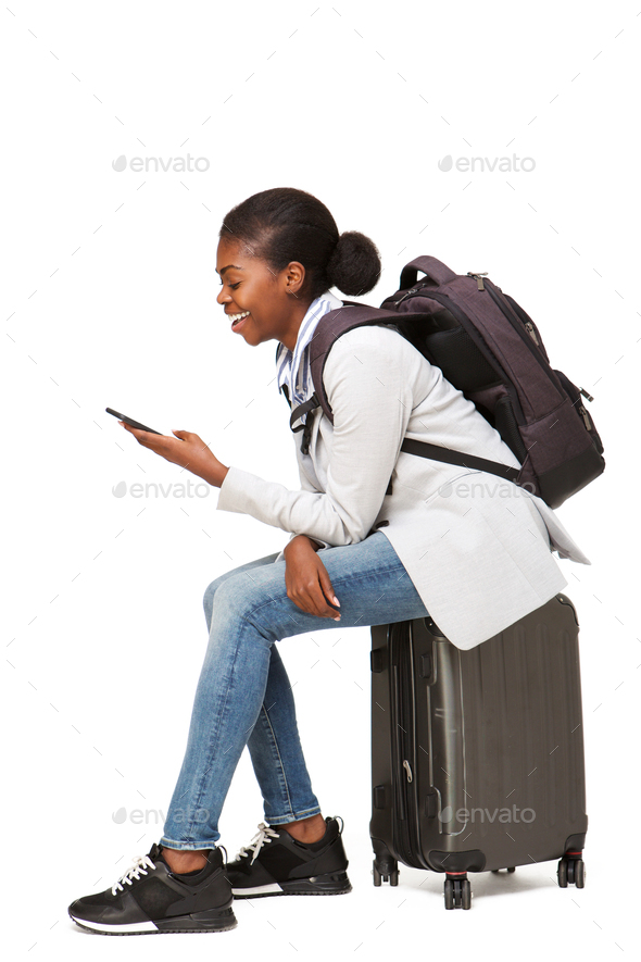 happy young african american woman sitting on suitcase and using mobile phone - Stock Photo - Images