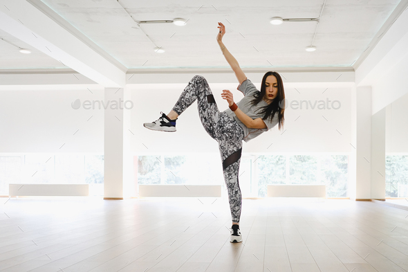 Athletic young girl performing sports and dance alone in a studio