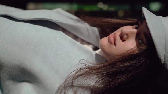 Nice Girl Posing at the Camera in a Blue Coat and a Cap Close Up alt