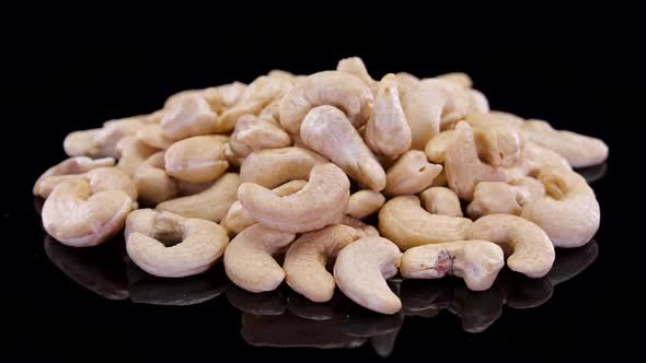 Cashew nuts rotating on a black background. Cashew, organic ecological nuts isolated.