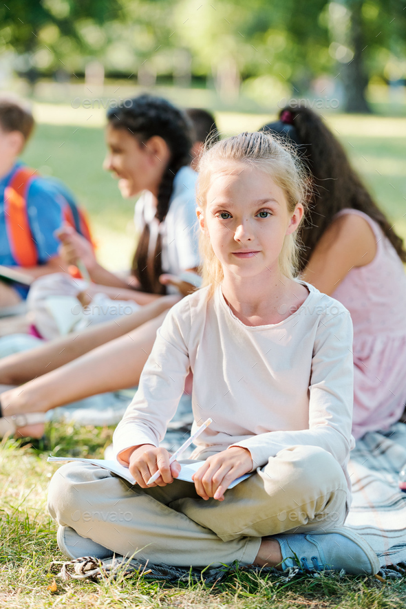 Portrait of content blond girl sitting at outdoor class
