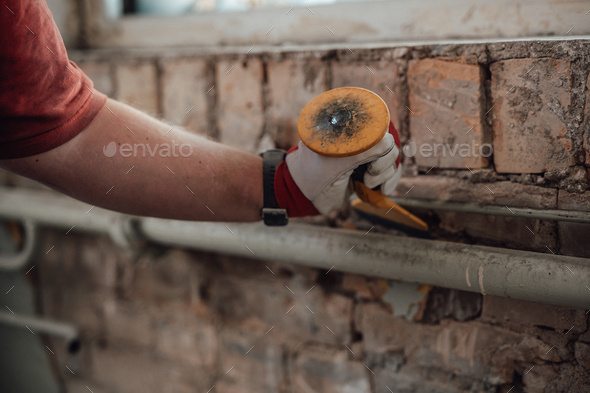 Builder\'s strong hands working with hammer and chisel at the construction site