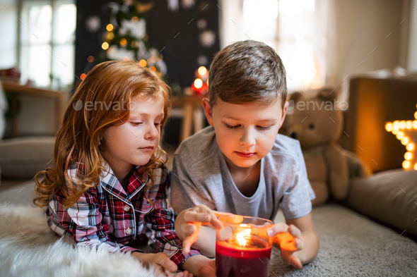 Small Girl And Boy Indoors At Home At Christmas Holding Candle Stock Photo By Halfpoint