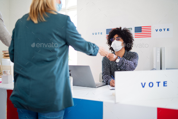 Group of people with face mask voting in polling place, usa elections and coronavirus.
