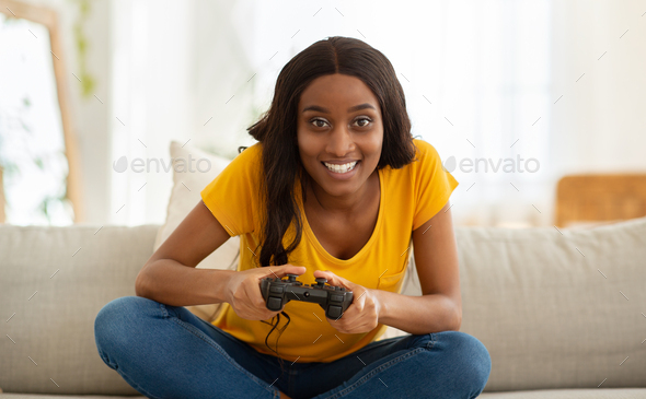 Happy young woman playing video game at home - a Royalty Free