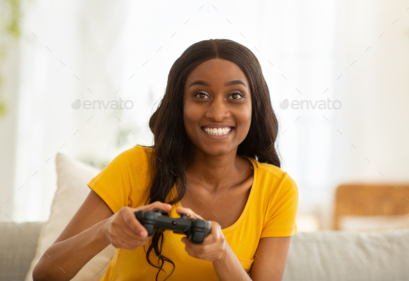 Weekend entertainments. Happy black lady with joystick playing online computer games indoors