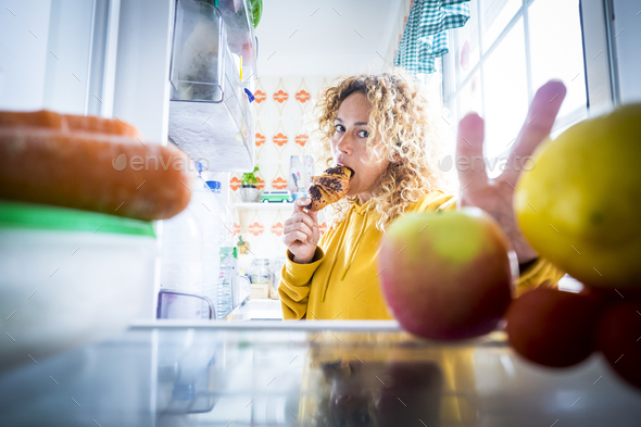 Alternaive inside view of Beautiful hungry adult woman from fridge