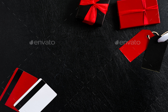 Mock-up Gift paper box and credit pay or discount colored cards on a black leather background, copy space. Top view. Black Friday Sale concept.