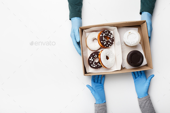 Waiter gives order during coronavirus epidemic and fast customer service. Client takes box of donuts
