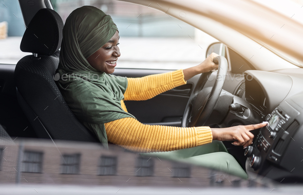 Car Playlist. Joyful Black Muslim Woman Driving Car And Listening Music