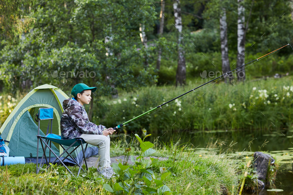Teenage Boy Fishing by Lake Stock Photo by seventyfourimages