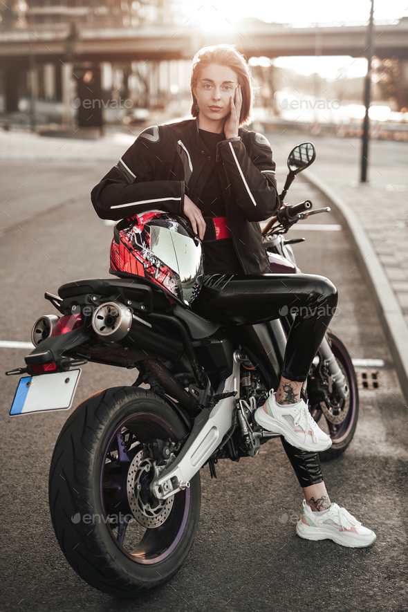 Pretty girl in a jacket sits on a purple motorbike with a red and black  safety helmet Stock Photo by fxquadro