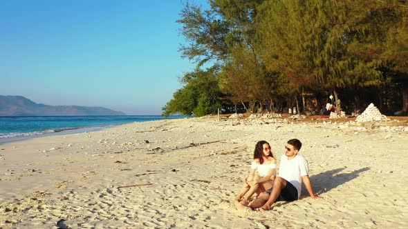 Two people engaged on marine seashore beach journey by blue ocean and white sandy background of Indo alt