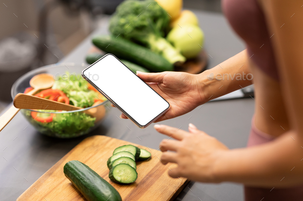 Woman Using Smartphone Cooking Healthy Dinner For Weight-Loss In Kitchen - Stock Photo - Images