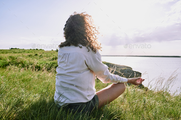 Meditating by tranquil lake - Stock Photo - Images