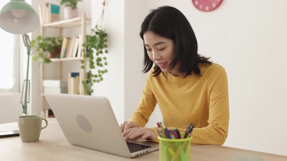 Young Asian Woman Working on Laptop Computer at Home alt