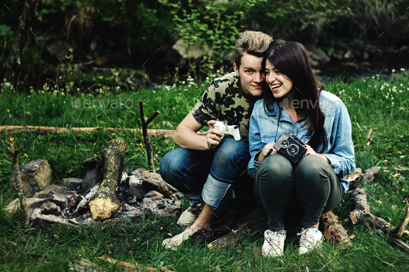 stylish beautiful couple camping smiling, with analog photo camera in spring sunny mountains