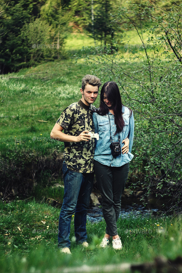 stylish beautiful couple camping smiling, with analog photo camera in spring sunny mountains