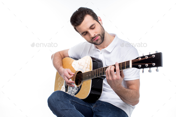 Handsome young man in white polo shirt playing guitar isolated on white