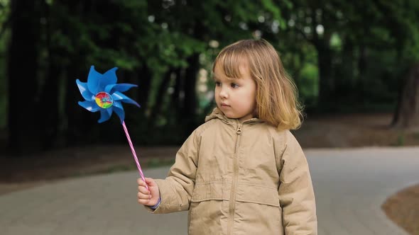 Portrait of Happy Cute Light Hair Little Girl with Windmill Toy. Girl Smiles and Play, Outdoor