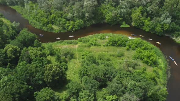 Aerial View of a Group of Kayaks Traveling on a Forest River on a Summer Day alt