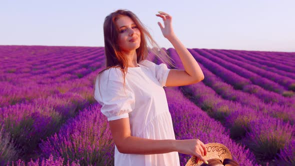 Beautiful Young Woman Wearing White Dress and Hat Standing in a Lavender Field