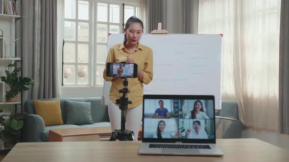 Asian Female Teacher Teaching English Online At Home With Students In Laptop Screen alt