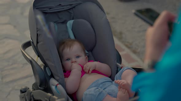 Mother Carries Stroller with Little Baby Walking on Beach alt