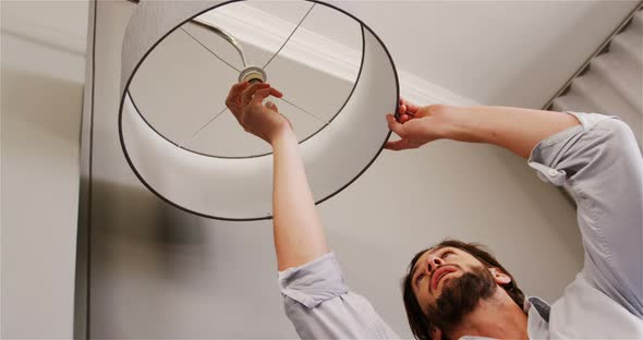 Man installing a bulb in living room alt