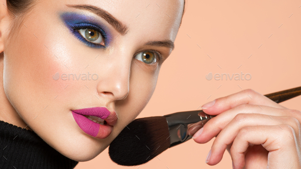 Portrait of a girl with cosmetic brush near face. Stock Photo by