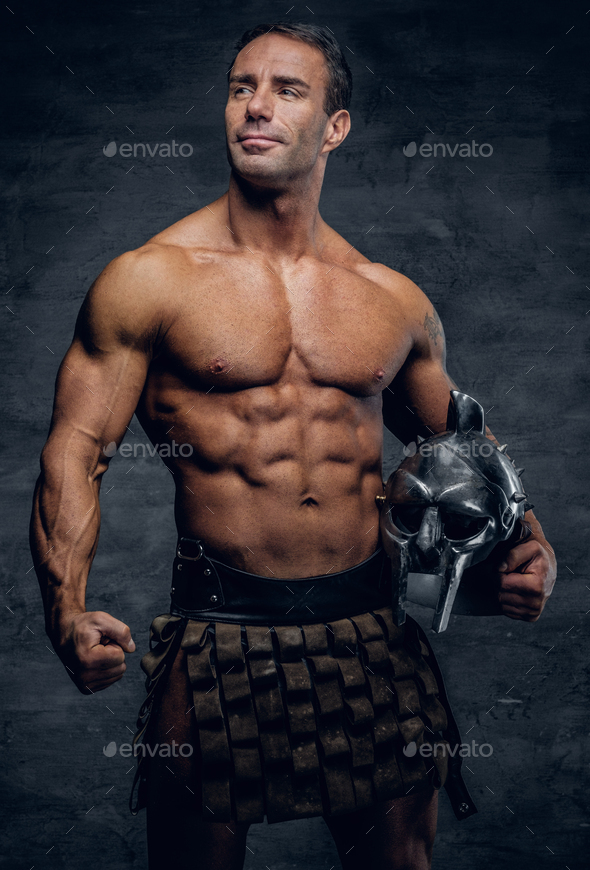 A man in a Rome soldier costume holds a silver gladiator helmet. Stock  Photo by fxquadro